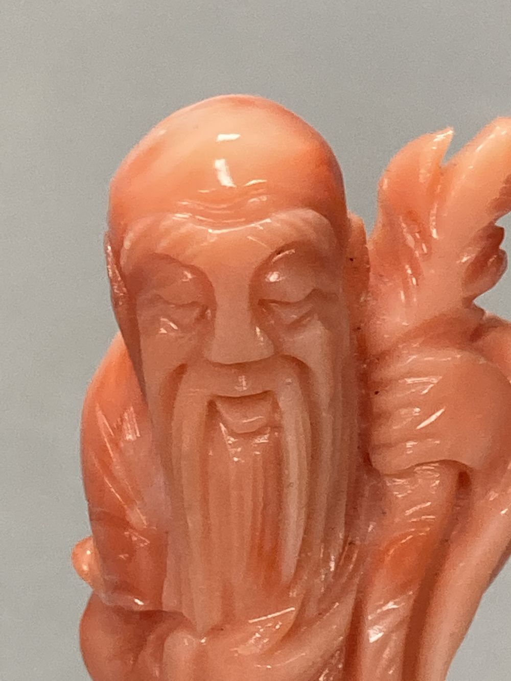 A Chinese carved coral figure of Shou Lao, on inlaid wooden stand, overall 81mm.